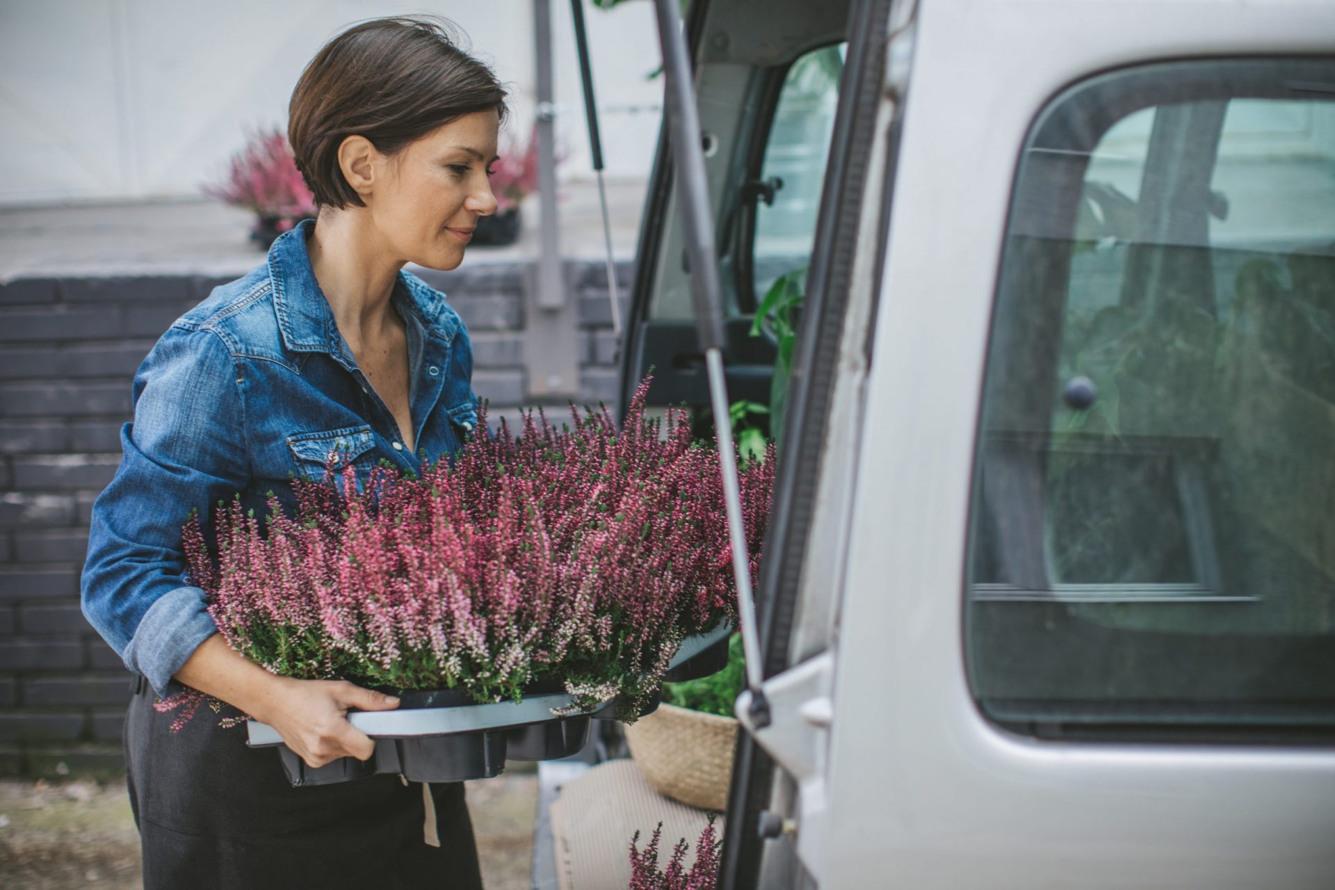 Frau packt Blumen in Auto