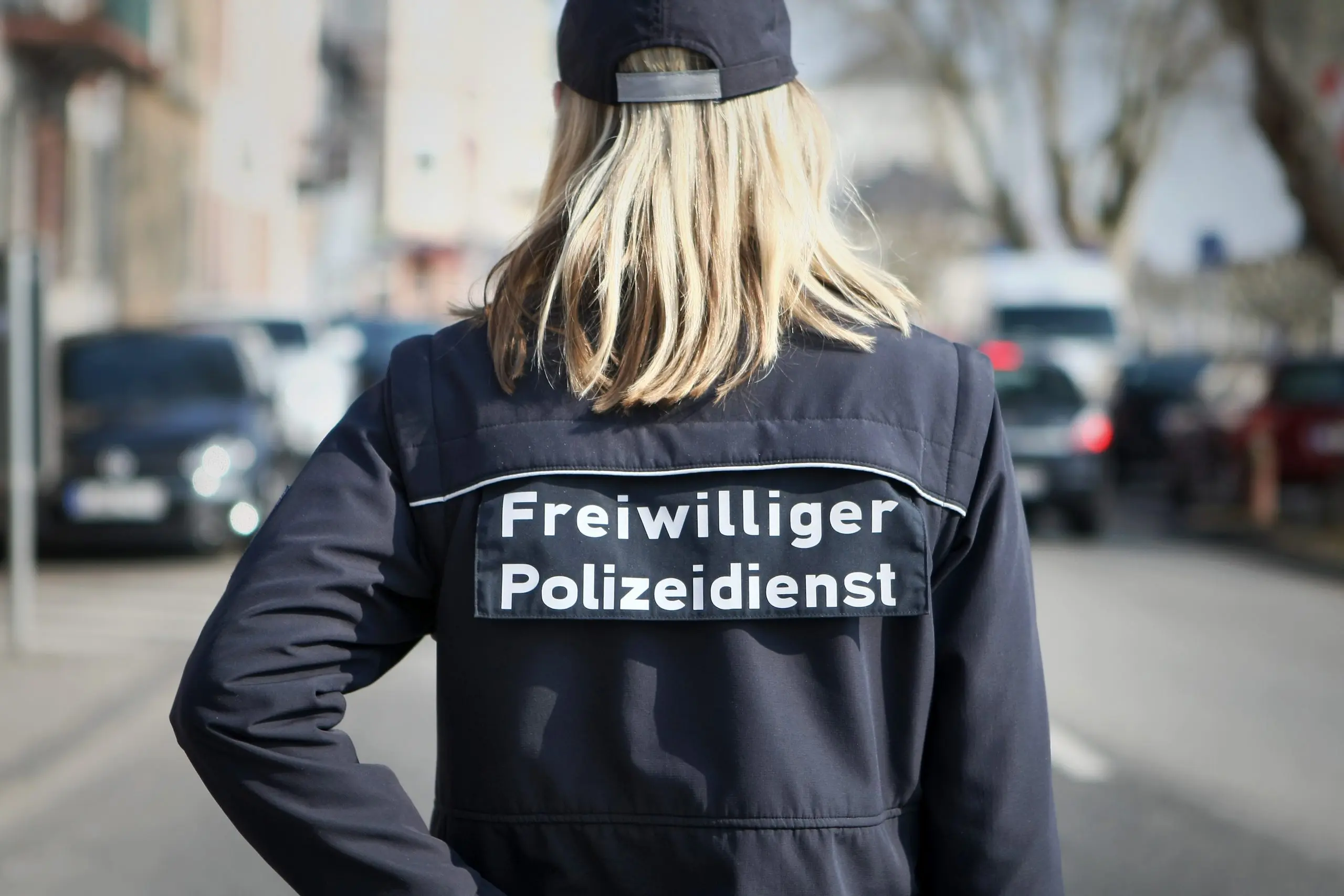Eine Frau mit dem Aufdruck auf der Jacke "Freiwilliger Polizeidienst"