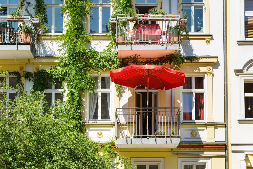 Haus mit Balkon und rotem Sonnenschirm