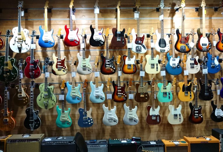 Wand voller hängender E-Gitarren in verschiedenen Farben