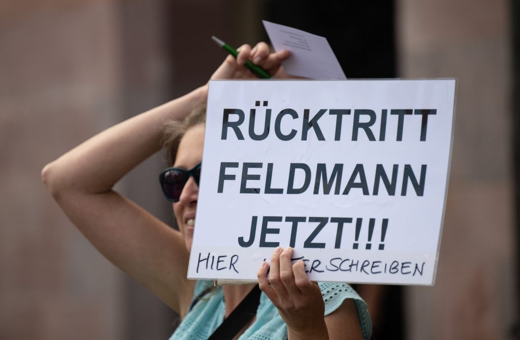 Frau hält Schild hoch: "Rücktritt Feldmann jetzt!!!"