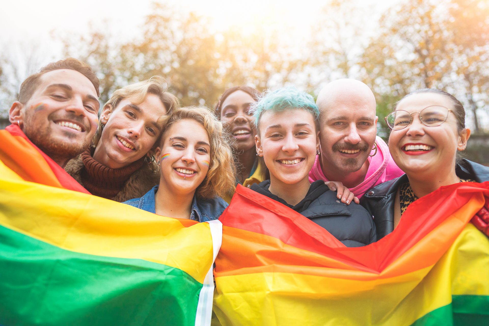 Gruppe queerer Menschen mit Regenbogen-Flagge