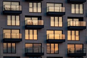 Die Abendsonne spiegelt sich in der modernen Glasfassade mit Balkonen