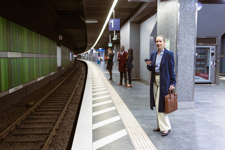 Geschäftsfrau, die auf einem U-Bahnsteig auf einen Zug wartet