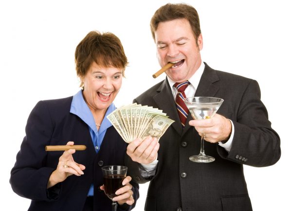 Business partners holding a wad of cash while smoking cigars and drinking cocktails.  Isolated.