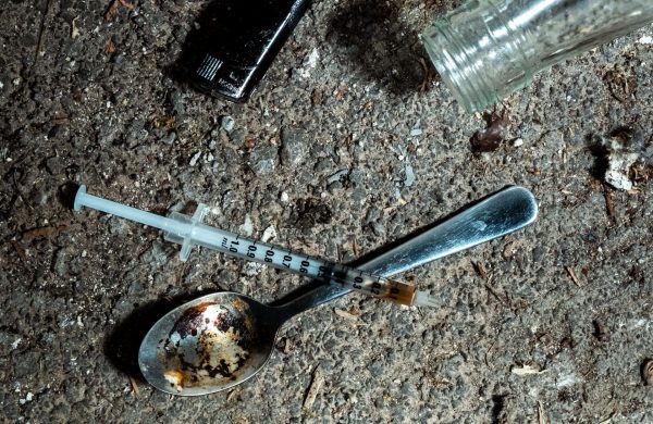 Night shoot of a spoon with used heroin, a lighter and a syringe on a floor. Symbol for drug addiction and substance abuse. 4K resolution video footage.