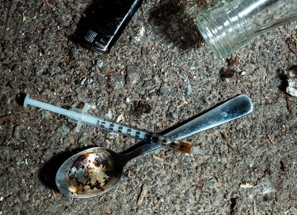 Night shoot of a spoon with used heroin, a lighter and a syringe on a floor. Symbol for drug addiction and substance abuse. 4K resolution video footage.